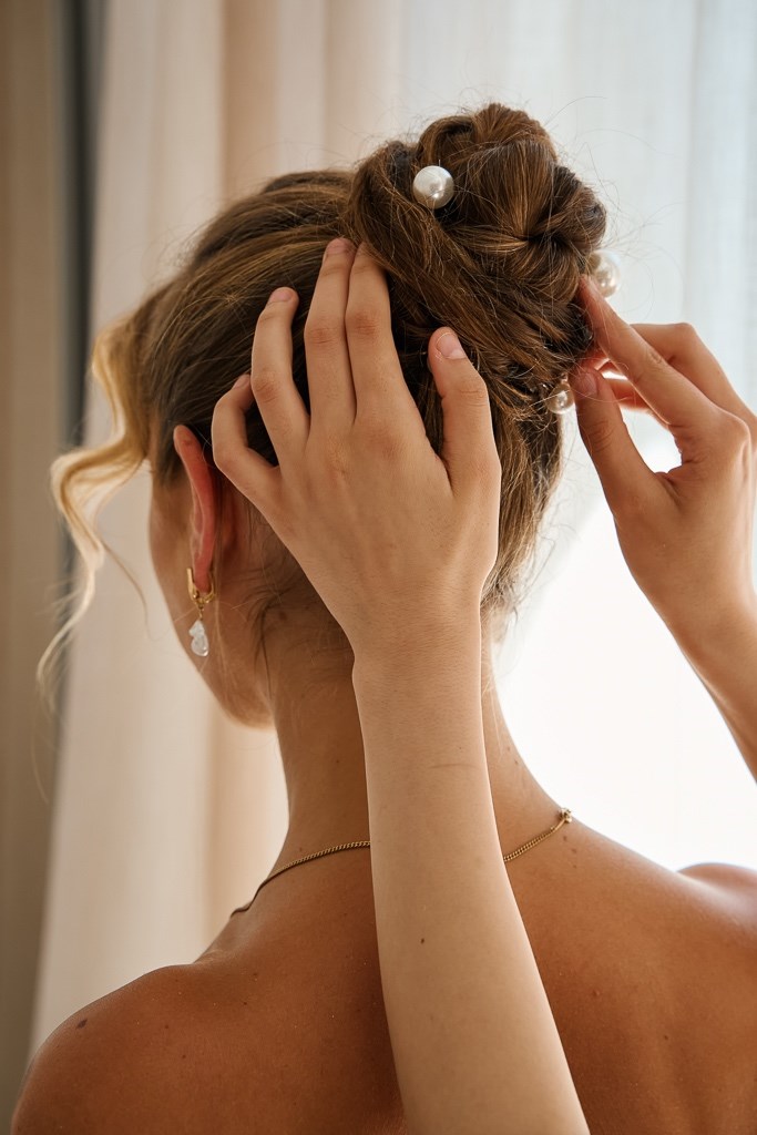 Hair Artist richtet von hinten den Dutt der Braut