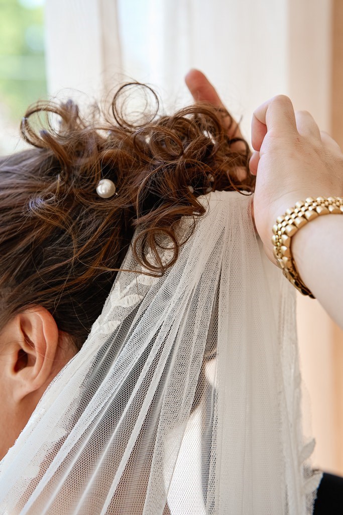 Hair Artist fügt Schleier in Brautfrisur ein