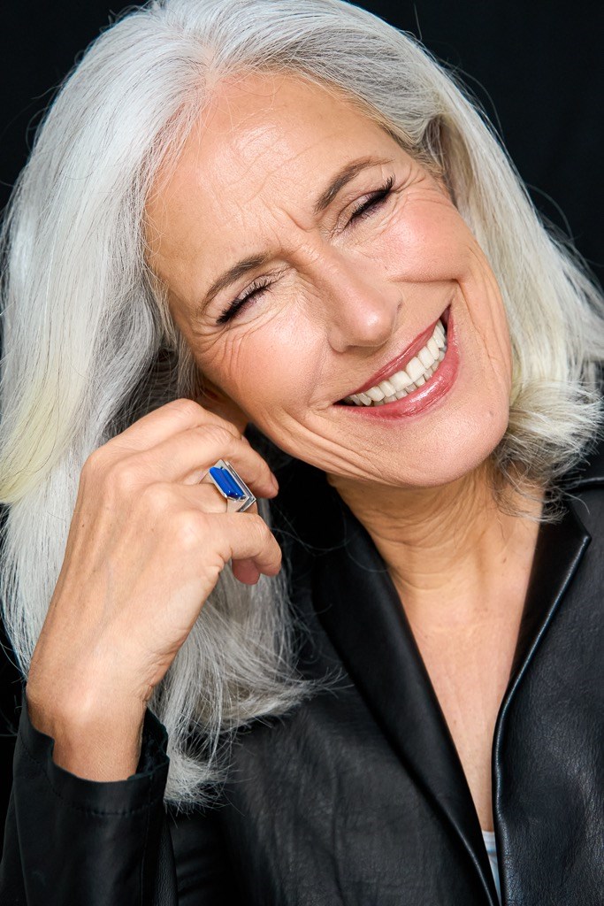 Best Ager Model lehnt sich auf Hand und lacht bei geschlossenen Augen