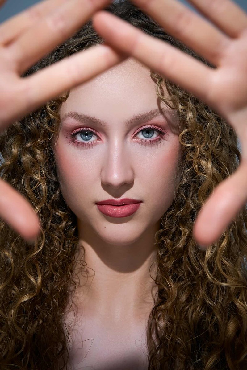 Model mit Händen vor der Kamera für Fokus auf dem Gesicht