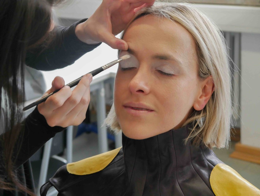 Blondes Model wird mit Pinsel am Auge geschminkt